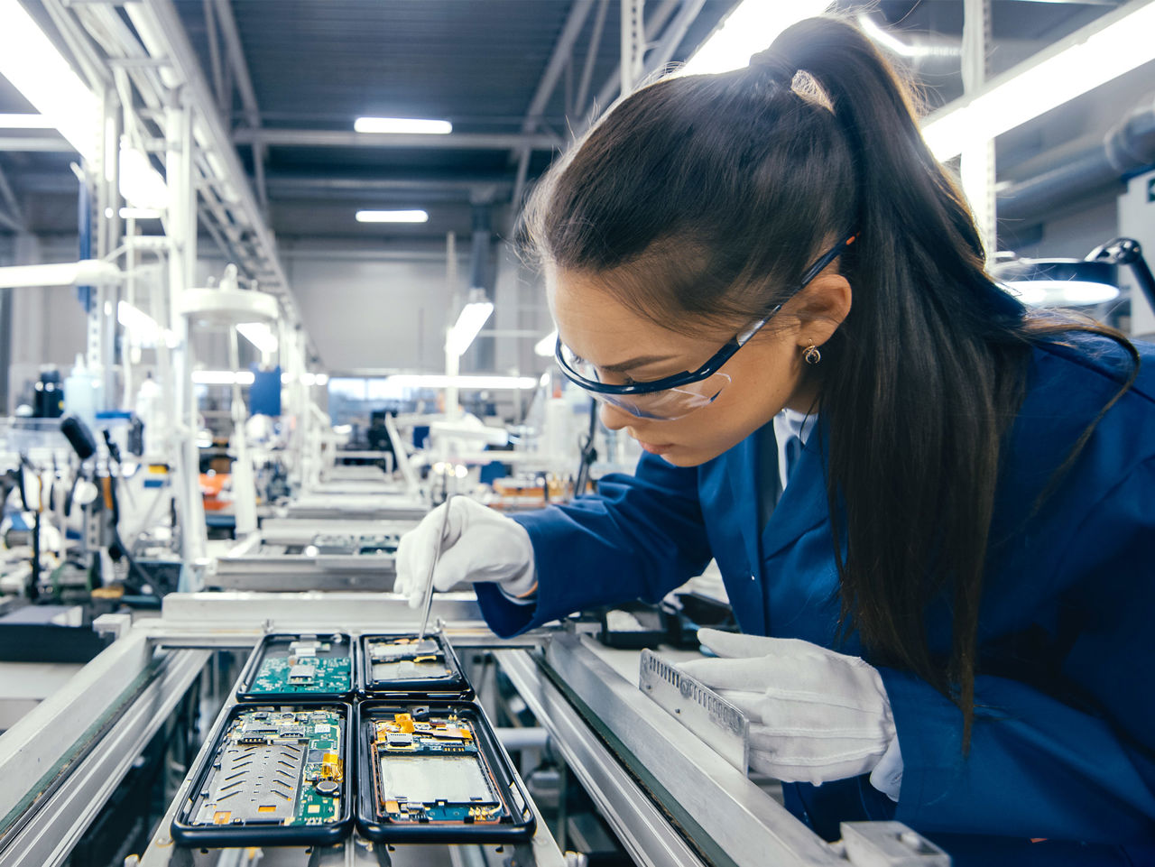 Inside a factory where a women is making some electronics.