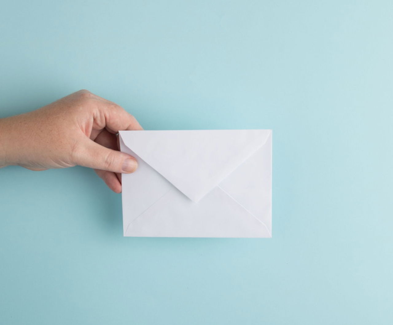 Hand holding white envelope